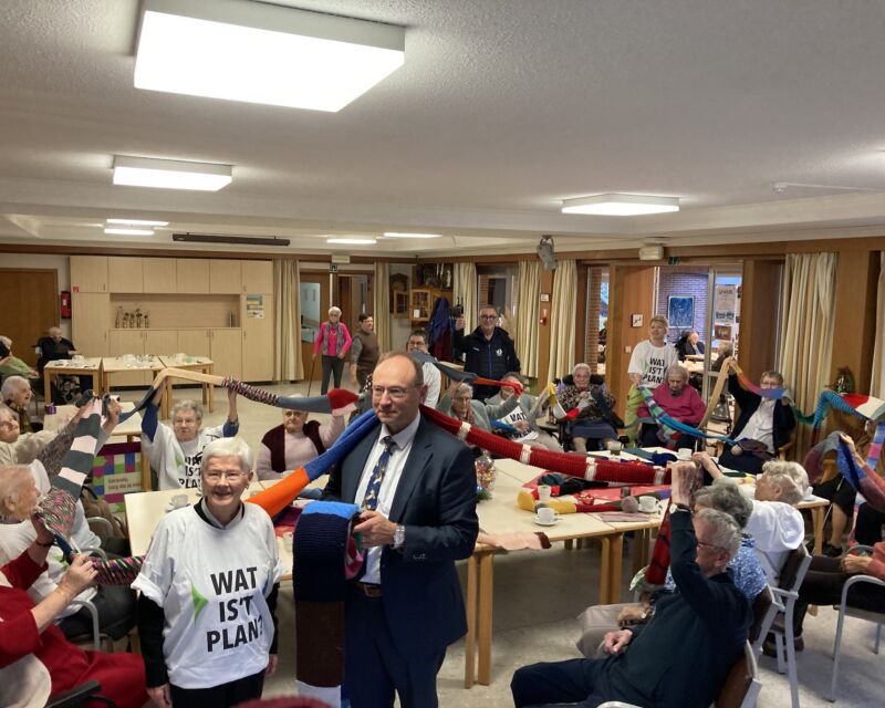 Algemeen directeur vzw Curando en algemeen overste Zr. Christianne De Craene steken samen de zorgvragers van WZC Sint-Jozef in Ruiselede de gebreide sjaal in de lucht.