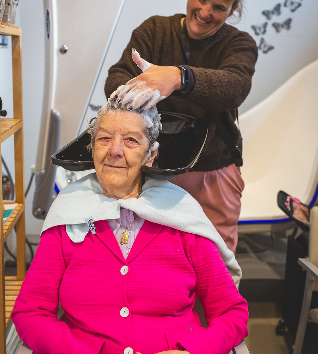 vrouwelijke medewerker wast haar van vrouwelijke zorgvrager